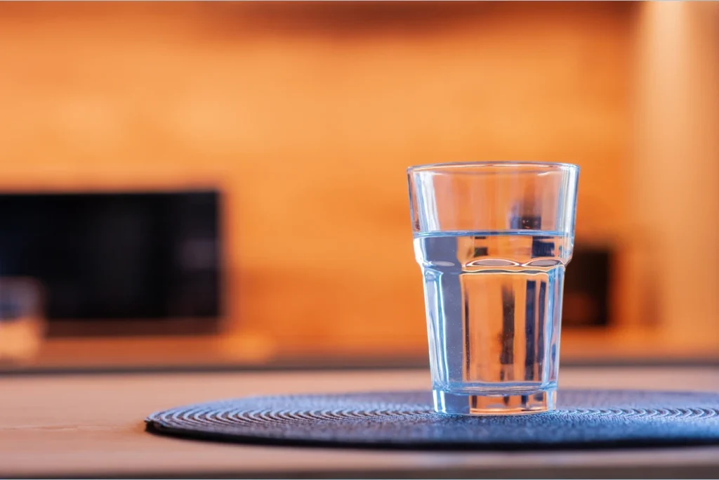 szklanka wody na stole 
któa pozwala się człowiekowi nawodnić
