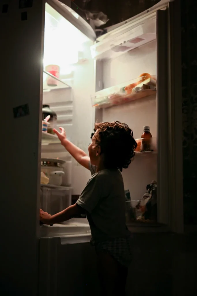 chłopak podchodzi w nocy do lodówki w celu przekąski 